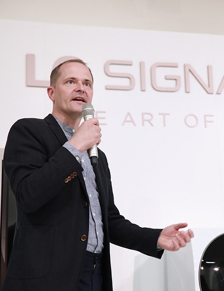 lg signature master designer torsten is talking on the main stage while pointing at lg signature washing machine at launching event in nordics