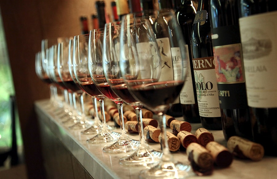 There are a lots of wines and glasses on the bar table.