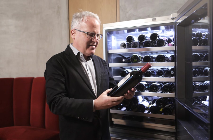 James Suckling is checking the wine in front of the LG SIGNATURE Wine Cellar.