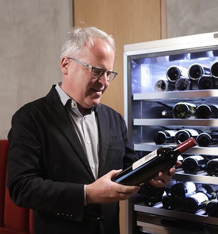 James Suckling is looking at a wine in front of LG SIGNATURE Wine Cellar.