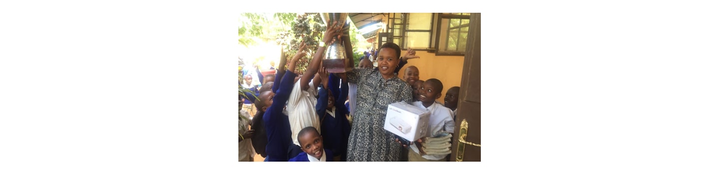 A teacher and students of a Tanzanian elementary school holding up FC Cambounet's trophy and the LG CineBeam projector donated to them to provide a better educational environment.