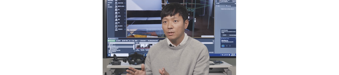 Ryu Byeong-gi, another featured digital designer at LG, explaining the role of a digital designer in front of his workspace equipped with a VR headset and large TV.