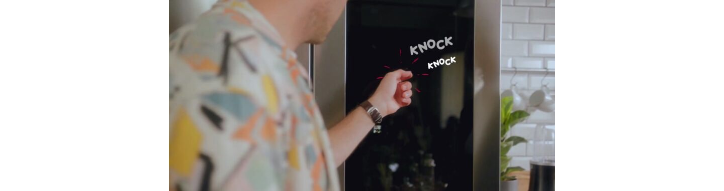 A man knocking twice on the LG InstaView Door-in-Door refrigerator’s window to light it up.