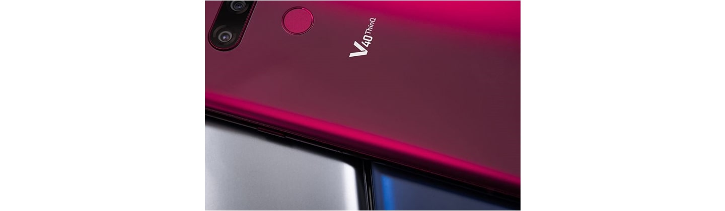 A Carmine Red LG V40 ThinQ is placed on LG V40 ThinQ smartphones in two different colors – New Platinum Grey and New Moroccan Blue.