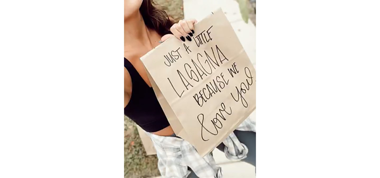 A Give LG Lasagna Love Challenge participant holding a bag with the phrase ‘Just a little lasagna because we love you’ printed on it.