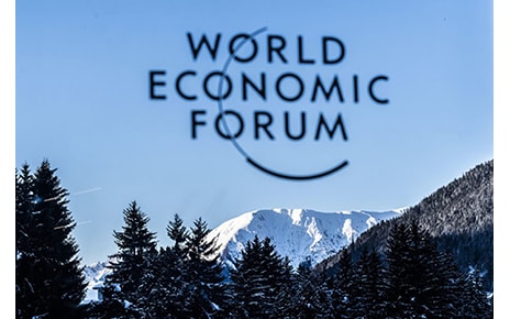 The logo of WEF with a view of Davos, Switzerland in the background.