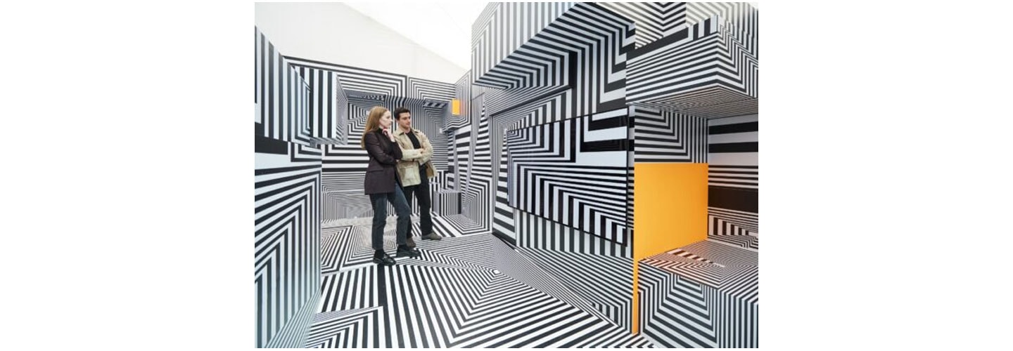 Two visitors taking a closer look at LG OLED-powered “Into the Maze” installation by the German artist, Tobias Rehberger