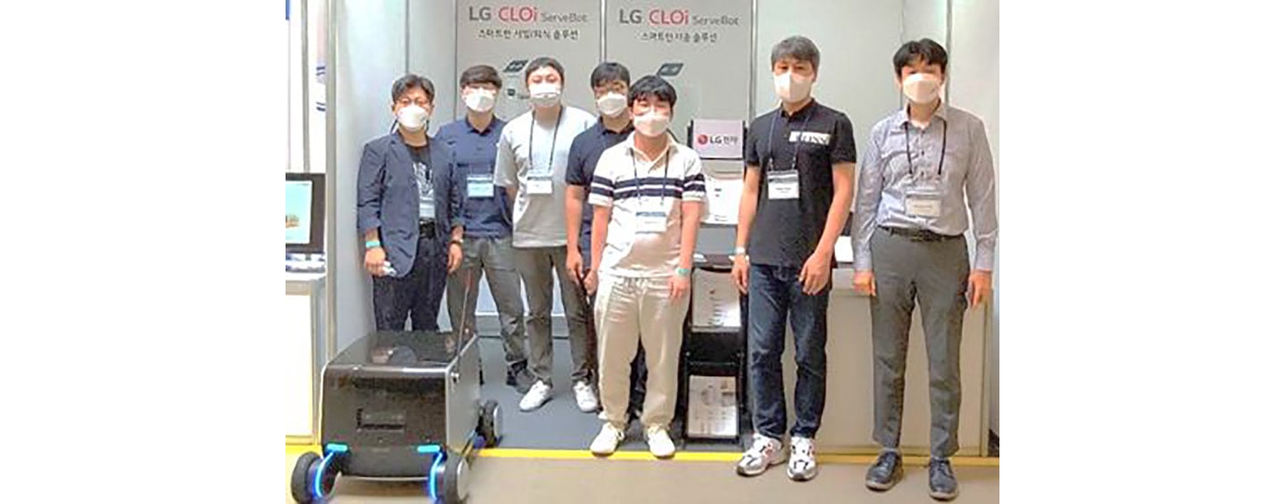 LG's robotics team posing with the indoor-outdoor delivery robot they recently developed.