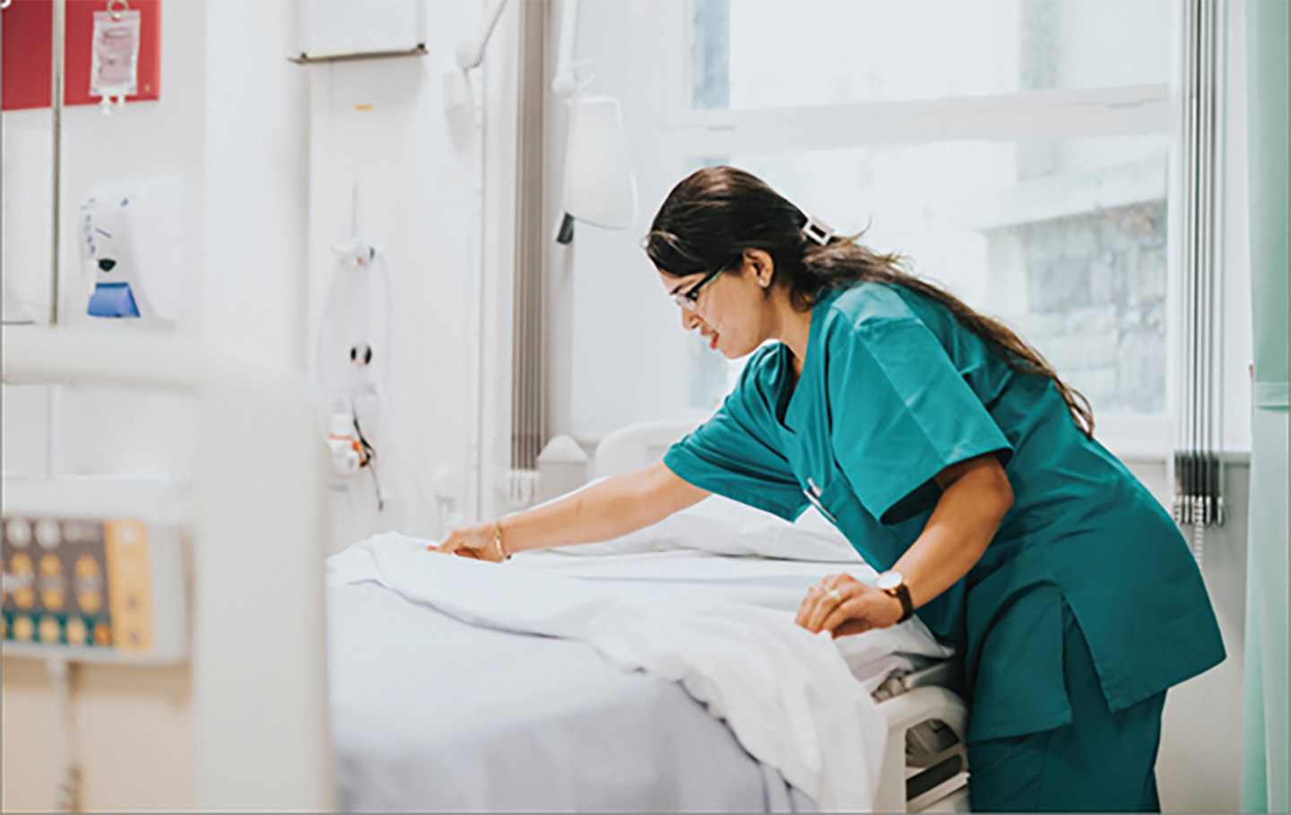 A healthcare worker making a hospital bed.