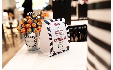 A sign for the LG gram Carnival stands on a table next to an LG-branded pot filled with lollipops