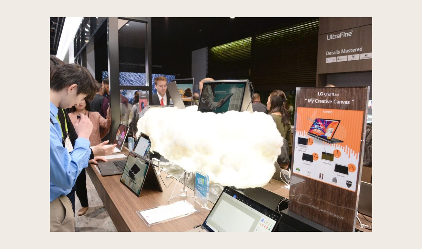 Display zone for the LG gram 2-in-1 laptop computer, there is one LG gram 2-in-1 model floating on a cloud prop while visitors to the zone test out the laptops.