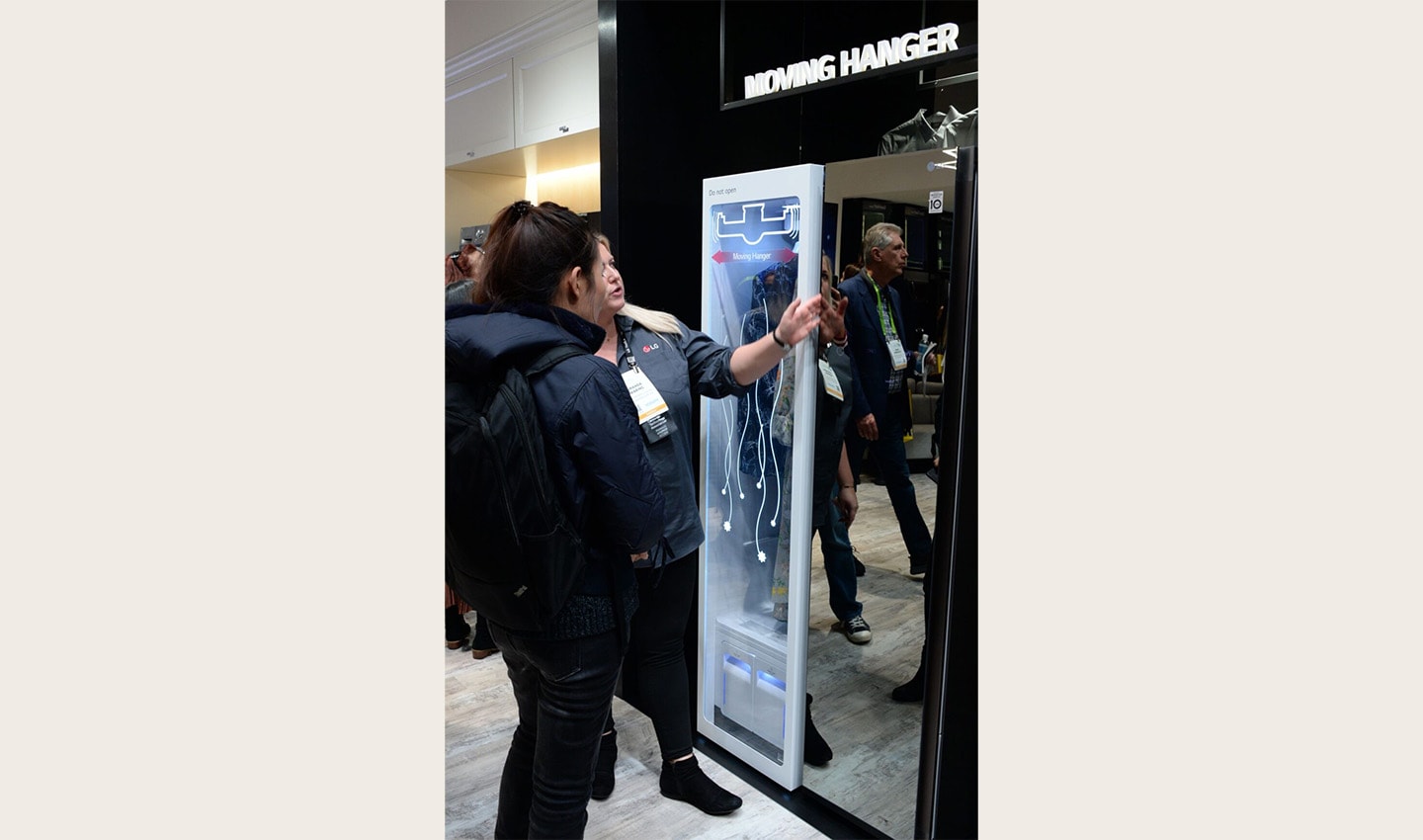Two women look at and try out a display of LG’s Moving Hanger technology at the LG Styler display zone.