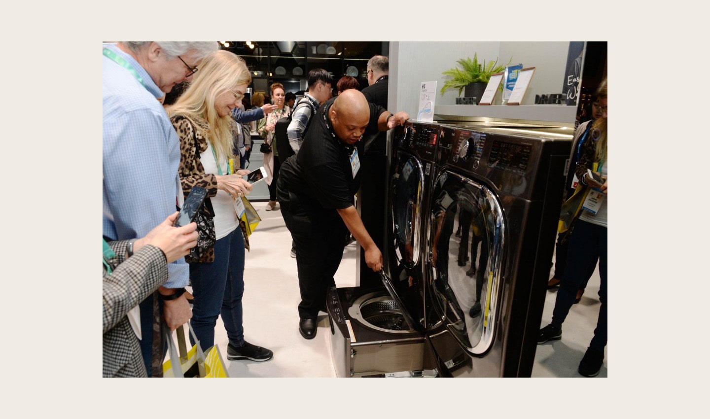 An LG representative demonstrates the second drum of an LG TwinWash appliance to onlookers at CES 2020