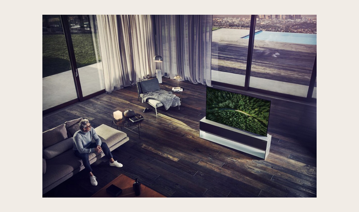 A man is sitting on his couch looking at a nature scene on an LG SIGNATURE OLED TV R
