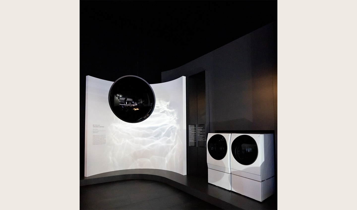 View of a pair of the LG SIGNATURE washer-dryers and a display to the left giving information about their features.