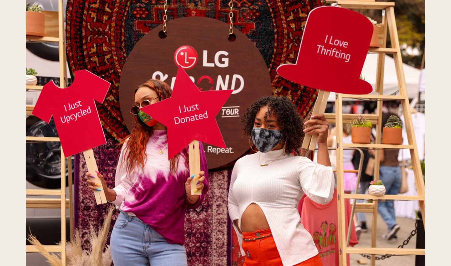 Two people holding up signs to help promote The Second Life Campaign and encourage more people to donate and upcycle their clothing