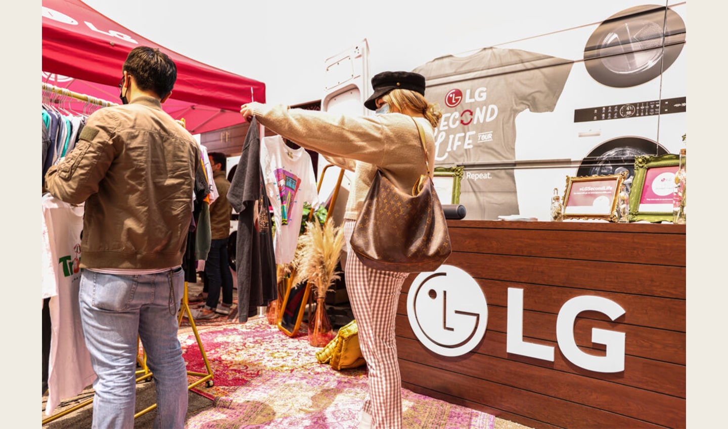 A woman carefully selecting between two shirts she discovered at the venue of The Second Life Campaign