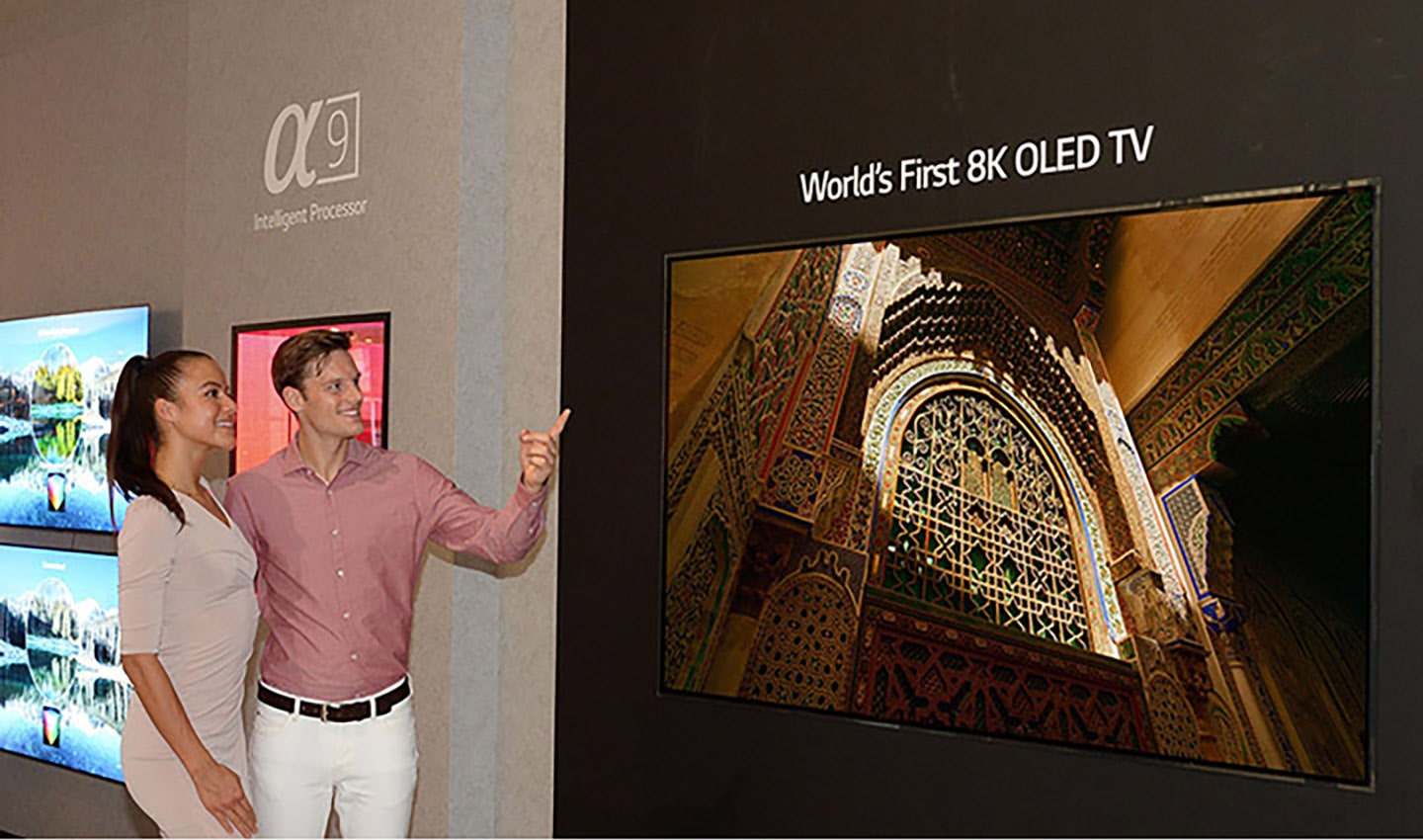 Another view of the World’s First 8K OLED TV with A9 Intelligent Processor display at IFA 2018, with a male and female model standing on the side pointing to the screen