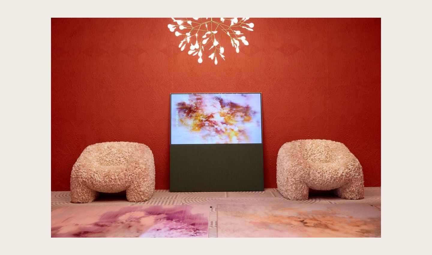 LG OLED Objet Collection Posé positioned between two sofas as it displays artwork in a red-themed showroom