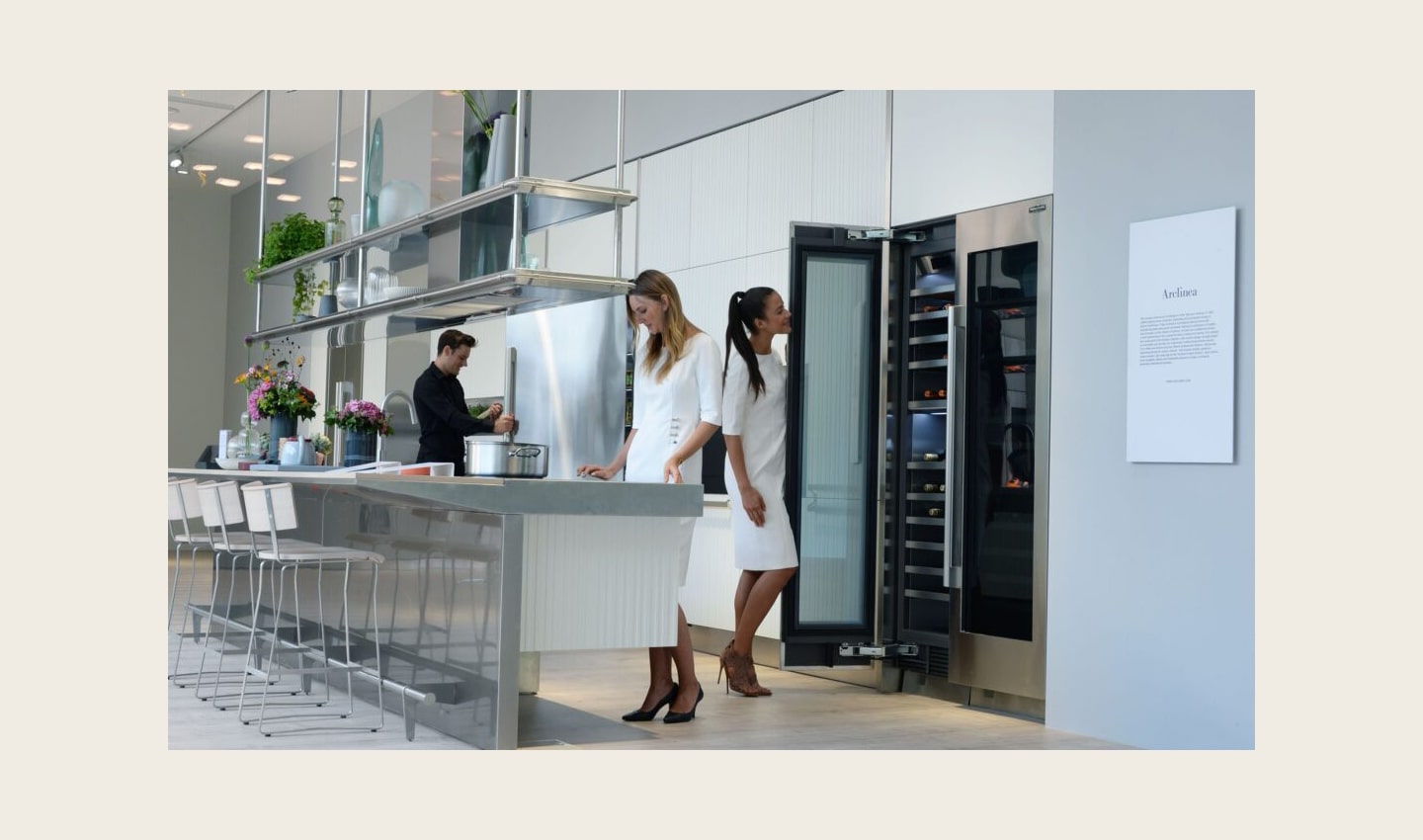 Another side view of the LG Signature Kitchen Suite display zone, three models are standing in the kitchen