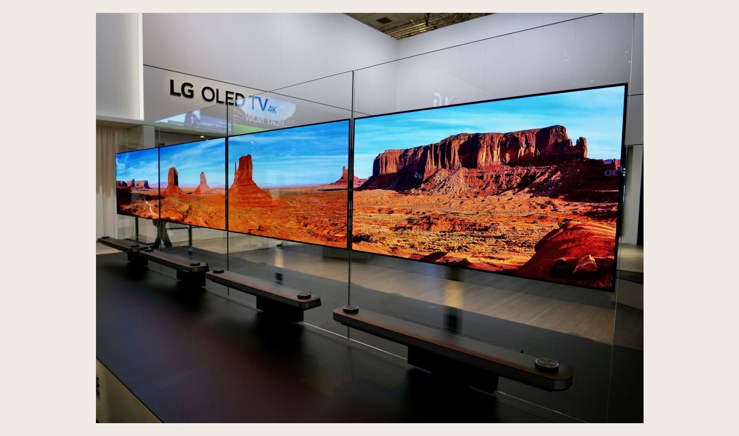 Another view of four LG SIGNATURE OLED TV W sets placed side by side on a display stand at LG's booth