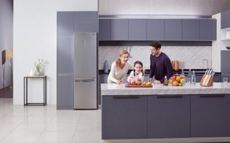 Little girl and her parents cutting fruit on the counter with LG Centum System™ bottom-freezer refrigerator in the background