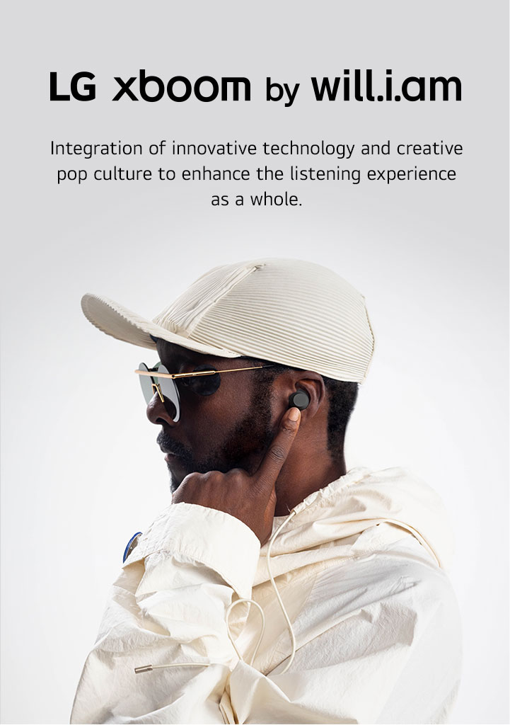 will.i.am in white outfit and sunglasses is facing right side pointing the earbud in his ear with his left index finger.