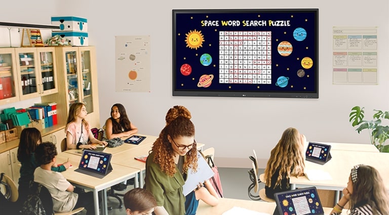 Class is being conducted in the classroom, and the class material screen which is displayed on the classroom wall's TR3DK Digital Board is being shared on the students' tablets.