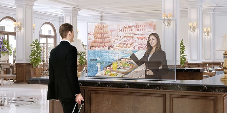A man is getting information through the Transparent OLED screen showing photos of the dessert menu.