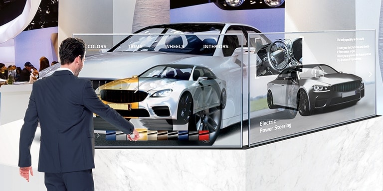 In a car exhibition hall, a man is changing the car’s color on the screen by touching the Transparent OLED Signage screen installed in front of the car.