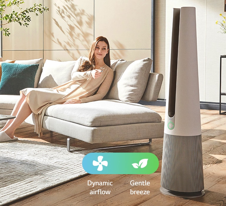 A woman sitting on the sofa in the living room is changing the product mode with the product remote control.