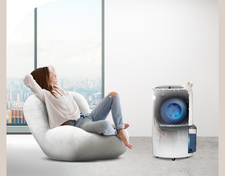 A woman is resting in a comfortable room where the dehumidifier is working, and inside the dehumidifier, it is seen that the UVnano fan is working.