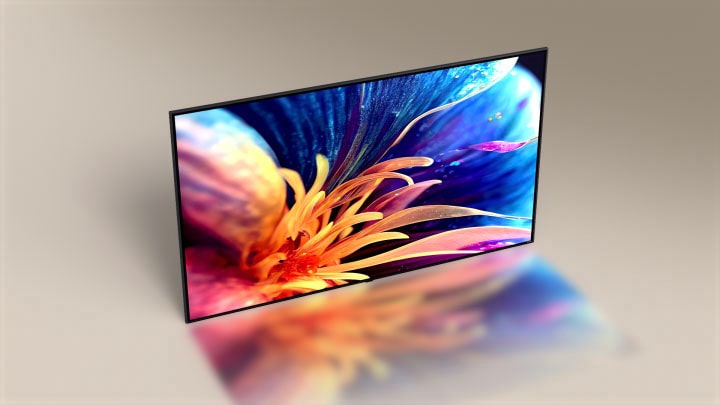 A super slim LG TV from bird-eye camera angle. The camera angle slides to show the front-face of the TV, displaying the picture of a colorful, zoomed-in flower.	