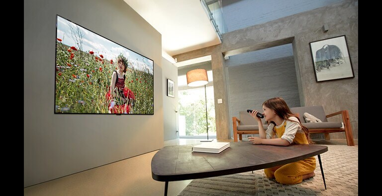 Girl is watching animation at its best quality on TV with her arm leaning on the living room table (move the slide)