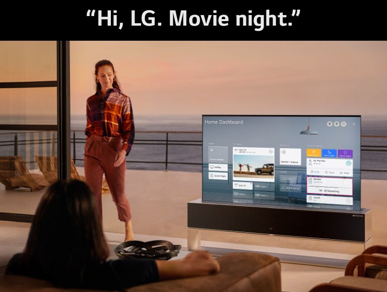 A woman is setting an optimized set for cinema via Home Dashboard on TV in the living room with an ocean-front terrace