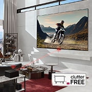 An LG OLED evo M4 within an angled perspective mounted on the wall of a bright, modern living room. A Zero Connect Box on a table in front, and a red Wi-Fi signal and red beam emitting towards the TV. The words "clutter FREE" in the bottom right corner.
