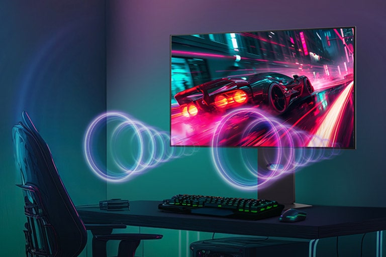 A monitor képernyőjén egy versenyzéses játék látható, miközben a hang a monitor alján található hangszórókból szól.