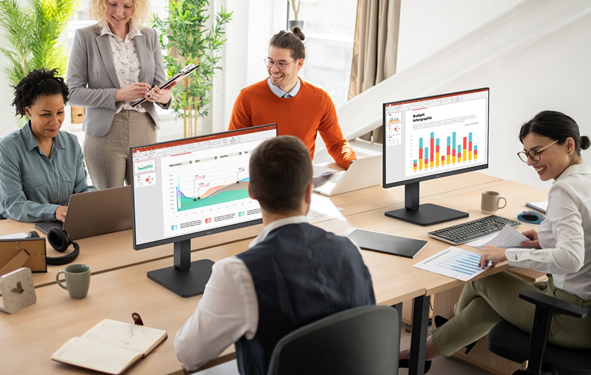 Irodai asztaloknál ülő és beszélgető alkalmazottak.