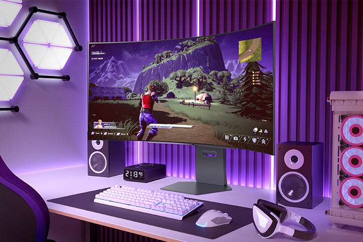 Ívelt gaming monitor, amely akció-kalandjátékot jelenít meg egy vibráló játékbeállításban, lila megvilágítással és a közelben egy PC-toronnyal.