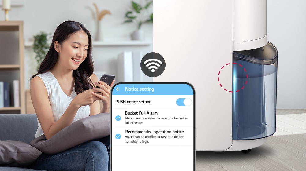 Wanita tersebut melihat ponselnya, tangki Dehumidifier LG Puricare™ sudah penuh dan lampu menyala.
