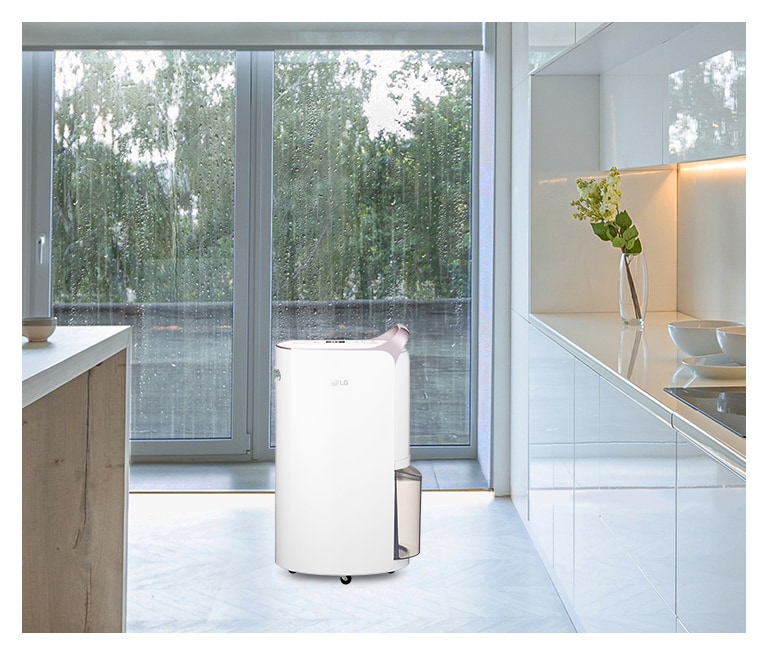 Menampilkan warna white rose gold yang elegan dari Dehumidifier LG Puricare™ yang ditempatkan di dapur dengan latar belakang hujan.