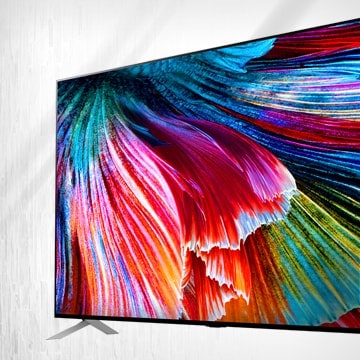 LG QNED MiniLED TV stood against a light backdrop with a close-up image of bright multi-colored petals on screen.