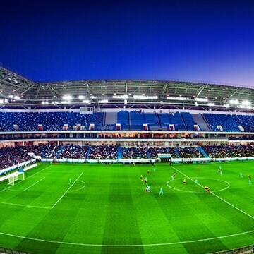 A wide-angled view of a football stadium with a full crowd and match in progress.