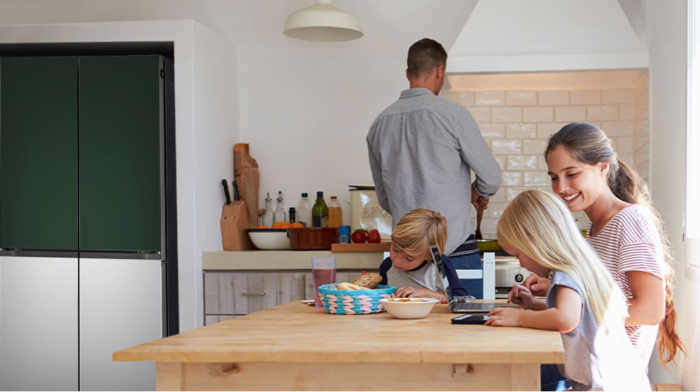 The whole family is sitting at the table preparing a meal. InstaView refrigerator installed on one side of the kitchen is creating cool air quickly.