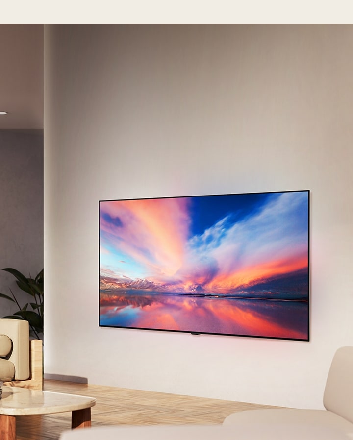 Il TV LG OLED C4 è rivolto a 45 gradi a sinistra e mostra uno splendido tramonto con una barca sul lago. Il TV è collegato a una soundbar LG tramite la staffa Synergy in uno spazio abitativo minimalista.
