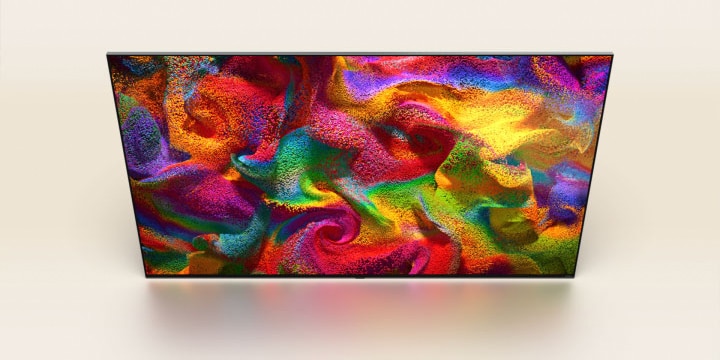 Delle particelle di colore esplodono sullo schermo, poi i pixel si trasformano lentamente in un primo piano di un muro dipinto con un motivo colorato sullo schermo del TV LG.