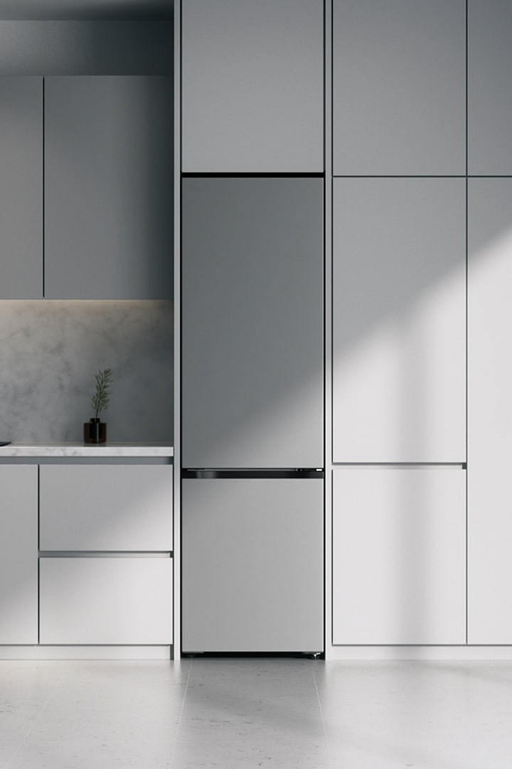 Frigorifero LG con congelatore inferiore nero opaco (gbbs726cpy) integrato in mobili grigi accanto al piano di lavoro in marmo con piano cottura a induzione e ampia finestra sulla destra.