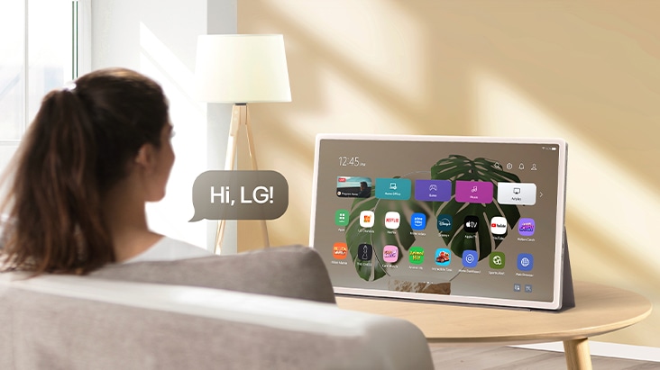 Persona usa il riconoscimento vocale su LG StanbyME 2; visibile fumetto con testo 'Hi, LG!'.