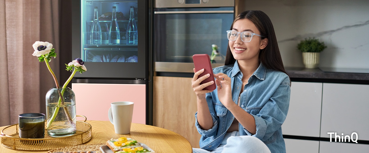 L'immagine di una donna che tocca il suo telefono in cucina, sullo sfondo un frigorifero MoodUP