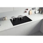 Foto dall'alto del piano cottura installato in una cucina bianca. Sul piano ci sono delle pentole.